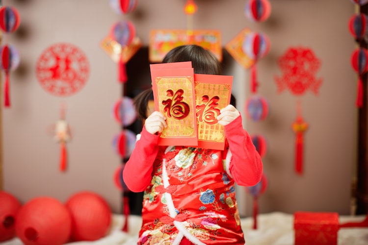 Niña con un sobre rojo tradicional del Año Nuevo Chino