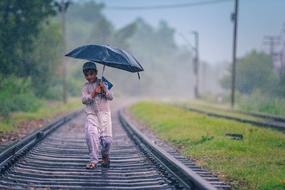 Boy Walking on Train Tracks in the Rain