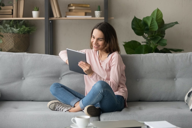 Woman Sitting on Couch With Tablet in Hand