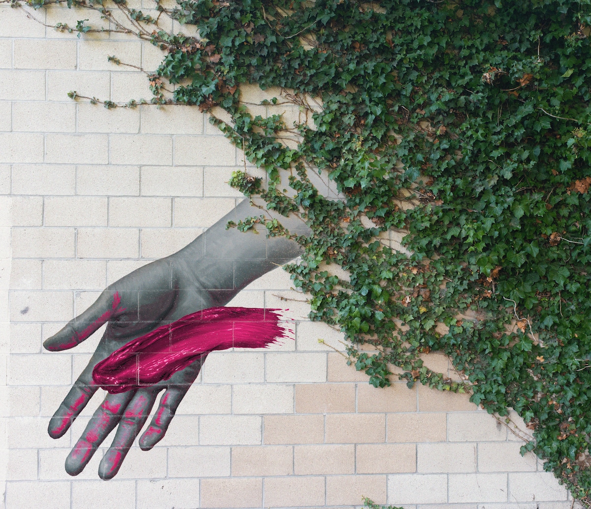 mano pintada en un muro con brochazo rosa