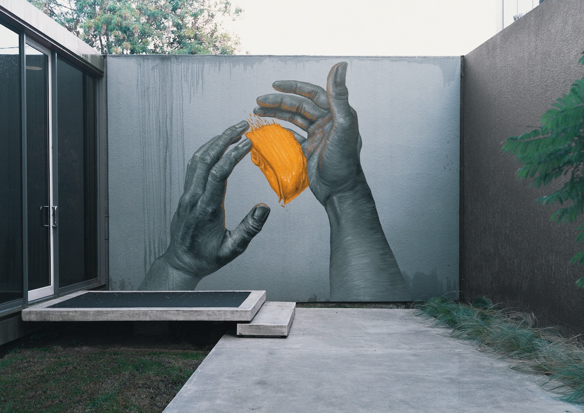 Two Hands Painted on a Wall with Yellow Brushstroke