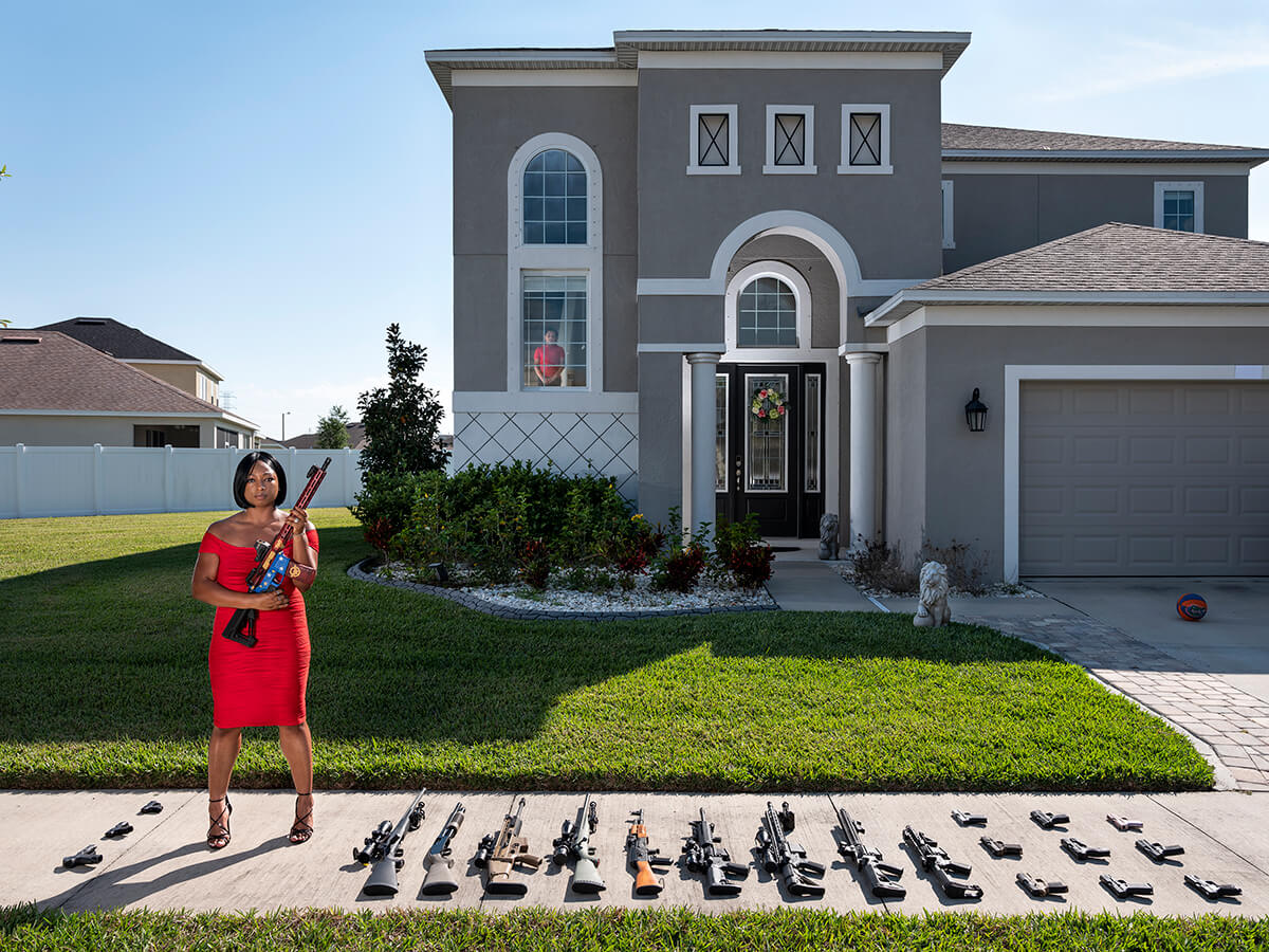 Woman Posing Outside of Her House with Her Guns