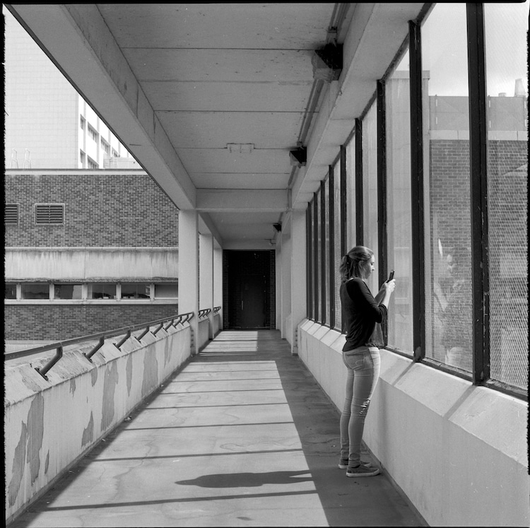 Black and White Photograph of a Girl Standing in a Window