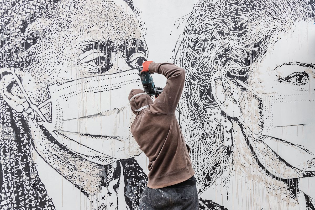 El artista callejero Vhils trabajando en un mural en un hospital de Oporto