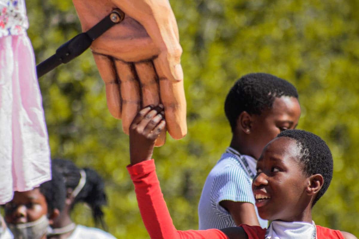 Young Boy Holding Little Amal's Hand