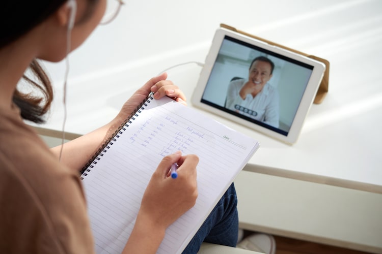 Woman Taking Notes During an Online Course