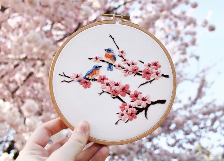 finished product of cherry blossom embroidery pattern in front of cherry tree