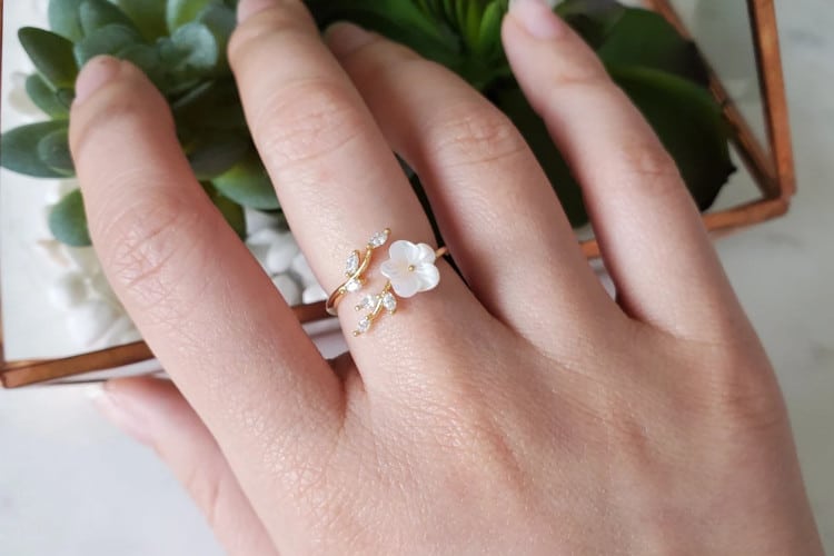 silver sakura flower ring on woman's hand