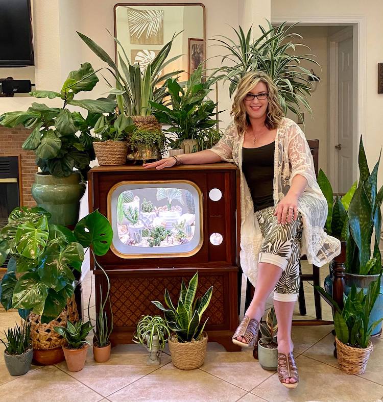 Femme posant avec des plantes et un terrarium télévision