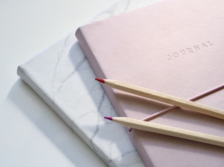 Journals Stacked on Top of Each Other With Pencils on Top