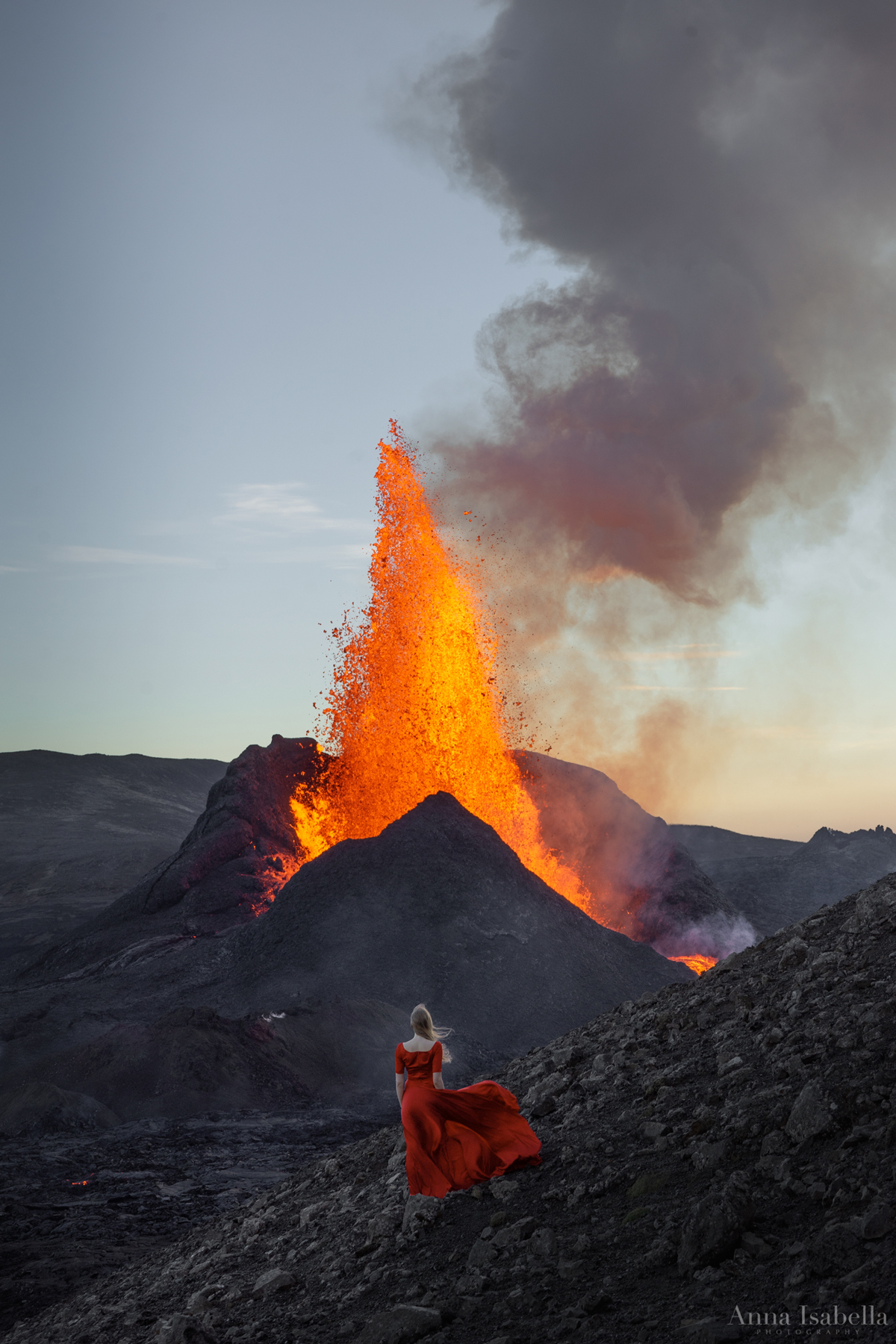 아이슬란드의 Fagradalsfjall 화산 앞에서 포즈를 취하는 빨간 드레스를 입은 여성
