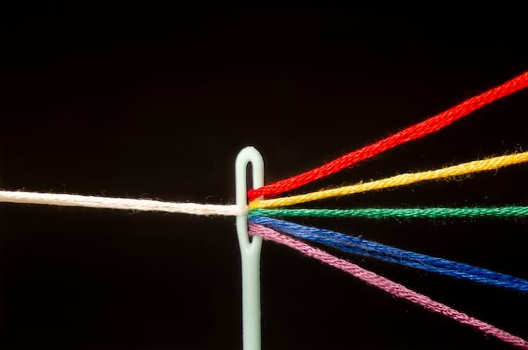 Needle With Rainbow Colored Thread Through the Eye