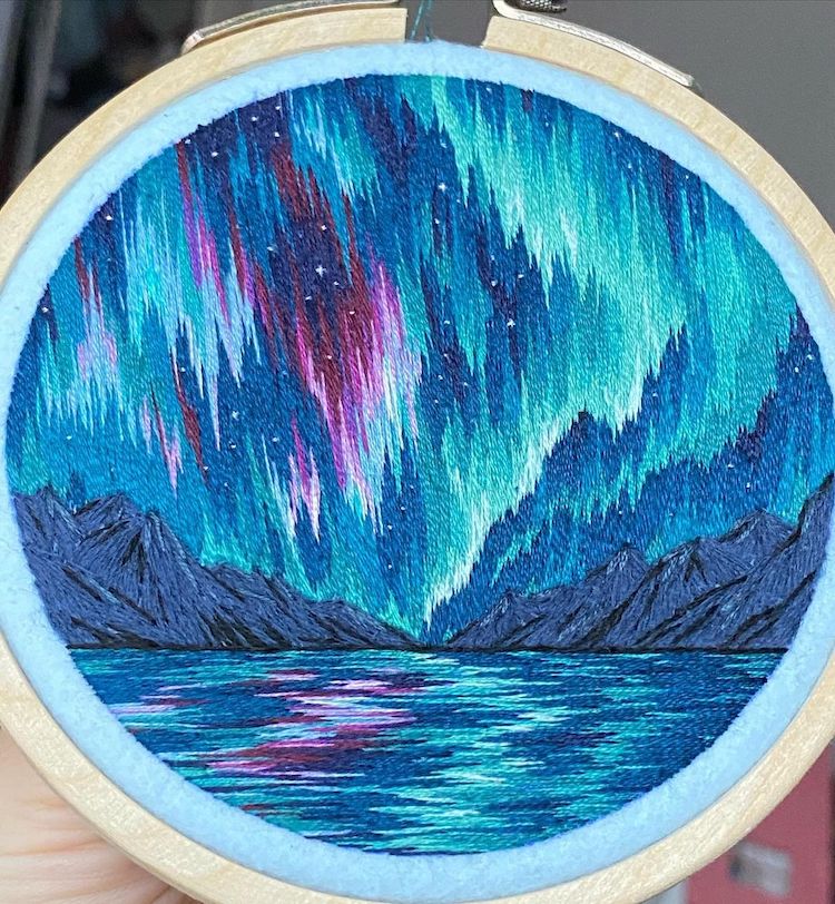 Embroidery art of a mountain landscape and the northern lights