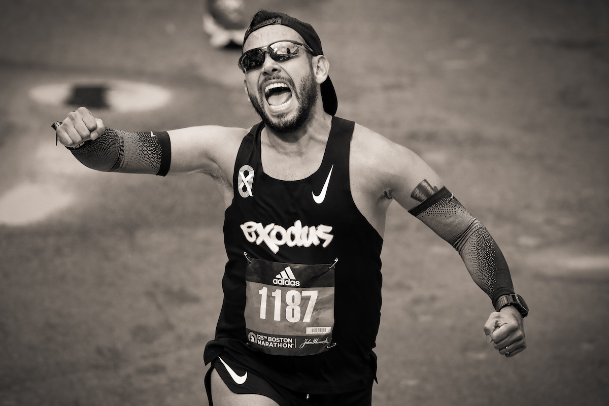 Man Triumphantly Crossing the Finish Line of the 2021 Boston Marathon