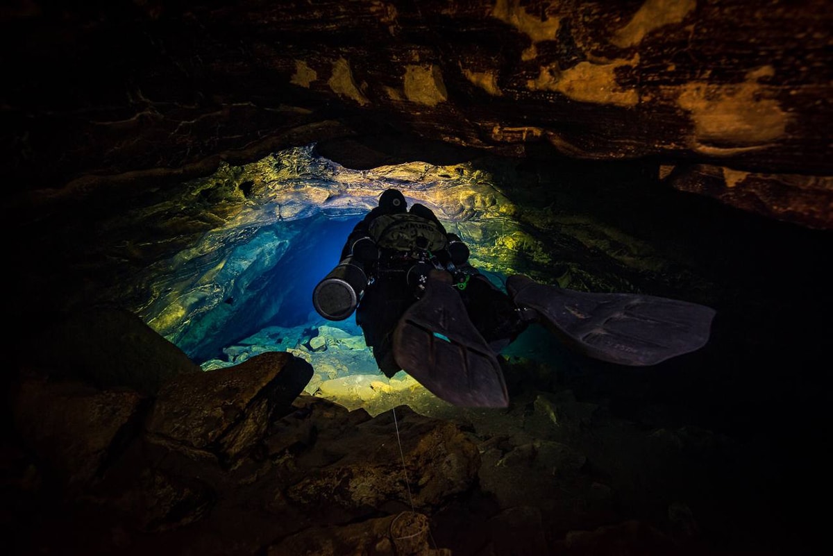 Nadador a través de una cueva submarina en México