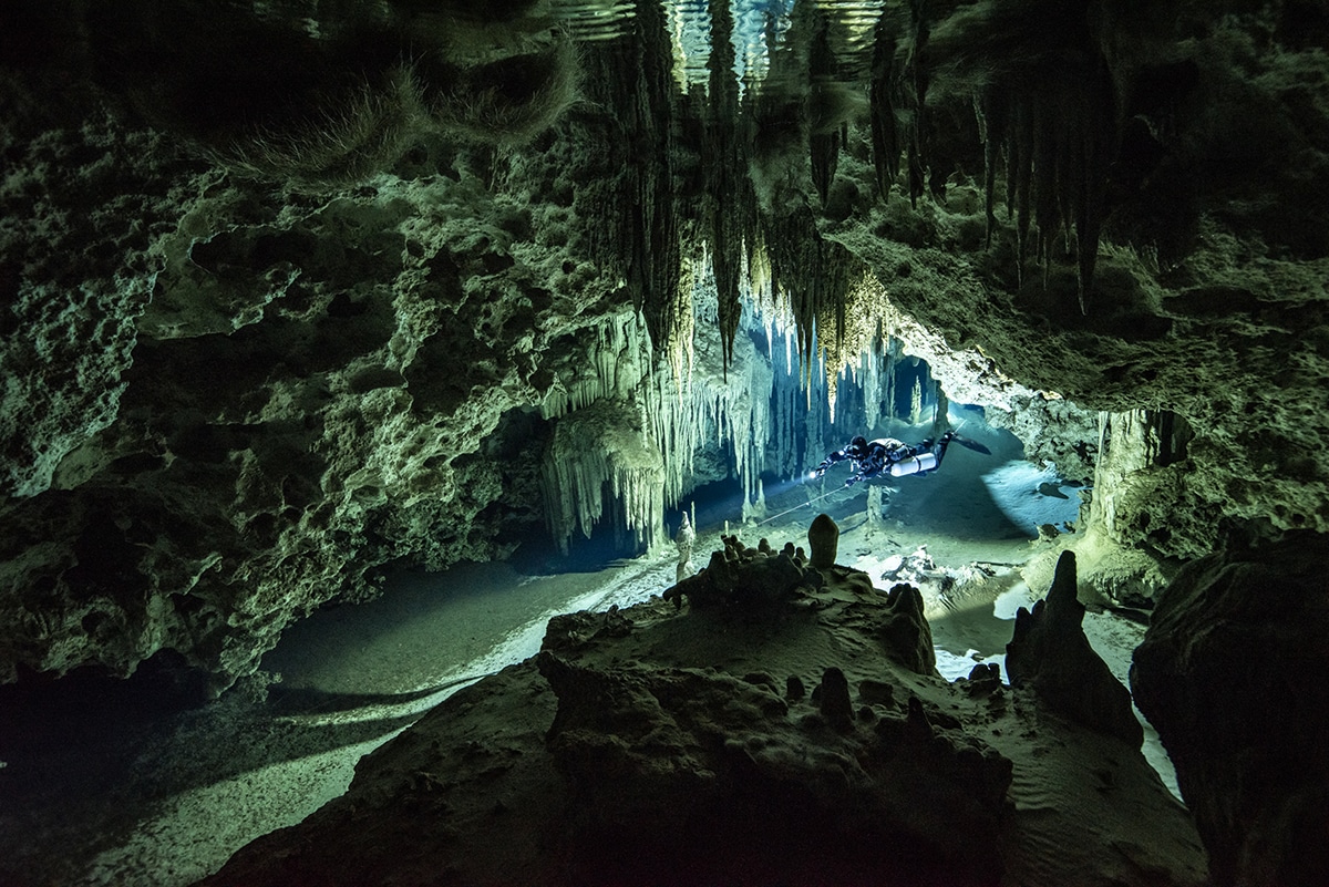 Nadador a través de una cueva submarina en México