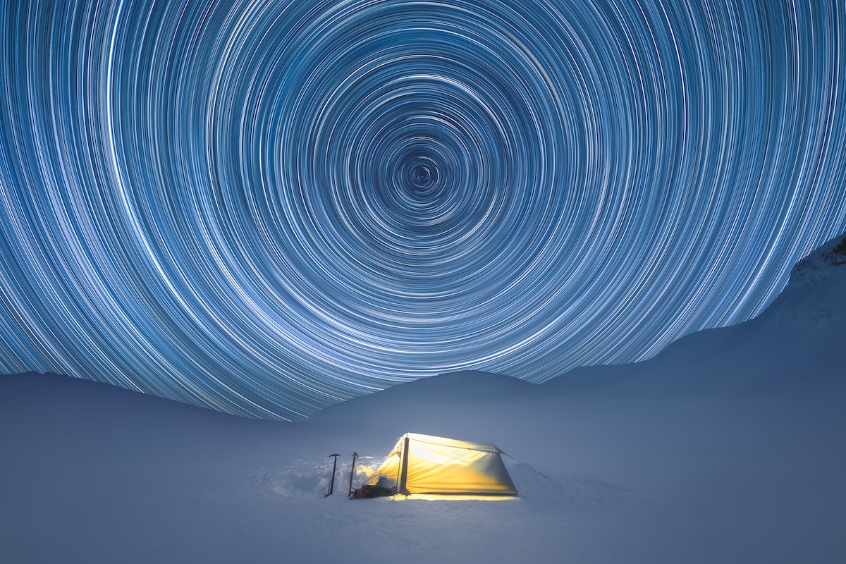Star Trails Over a Lit Up Tent on a Mountain