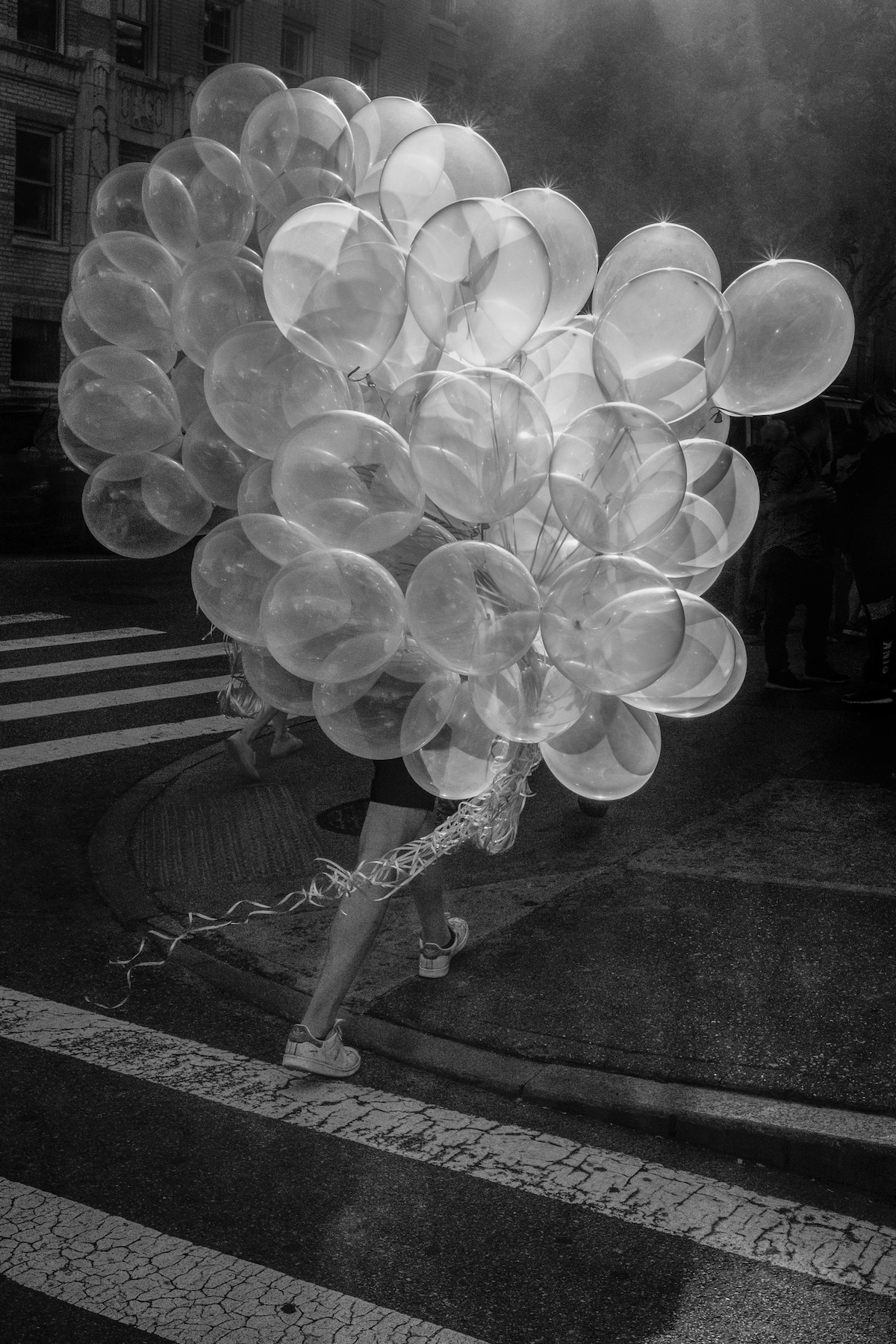 Foto en blanco y negro de una persona con globos cruzando la calle