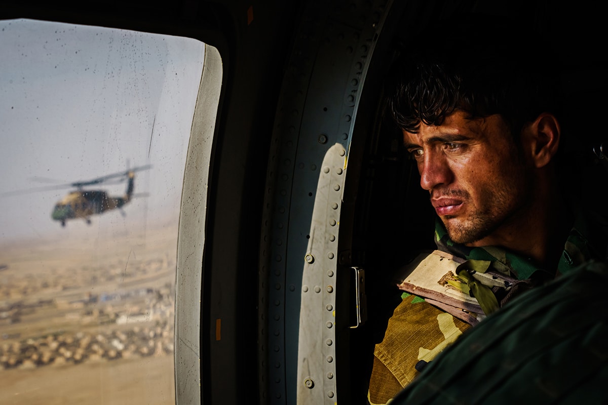 A soldier surveys the terrain out of the window of a UH-60 Black Hawk during a resupply flight toward an outpost in the Shah Wali Kot district north of Kandahar, Afghanistan.