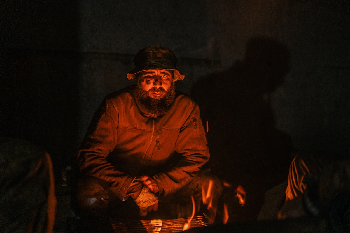 Soldado se calienta las manos junto an una fogata en la acería de Mariúpol