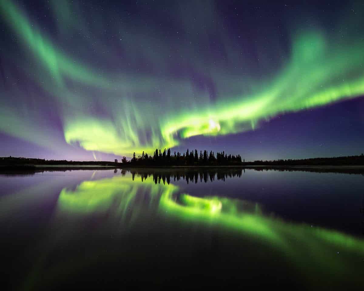 Northern Lights are reflected in a lake in Alberta, Canada