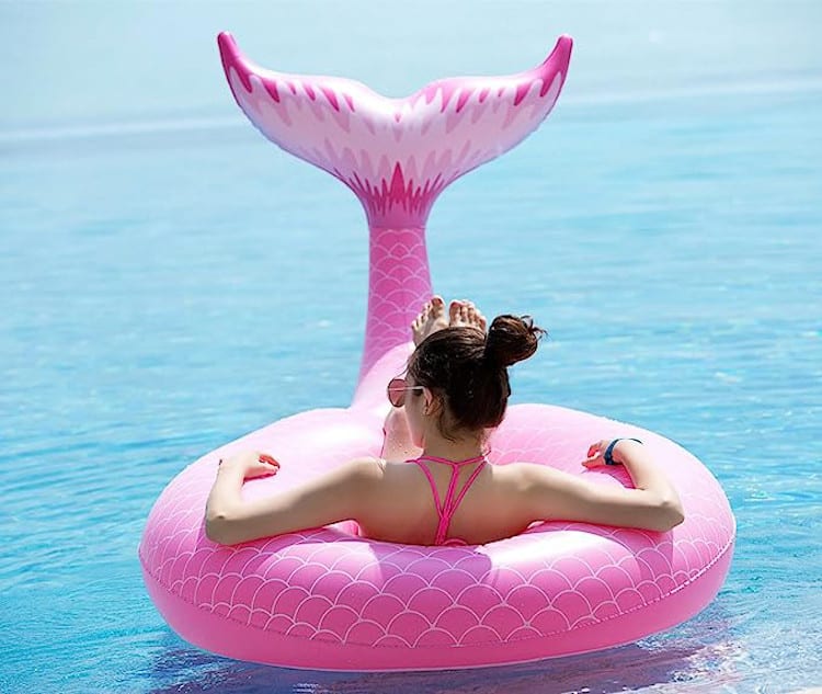 Woman using a pink mermaid tail pool float