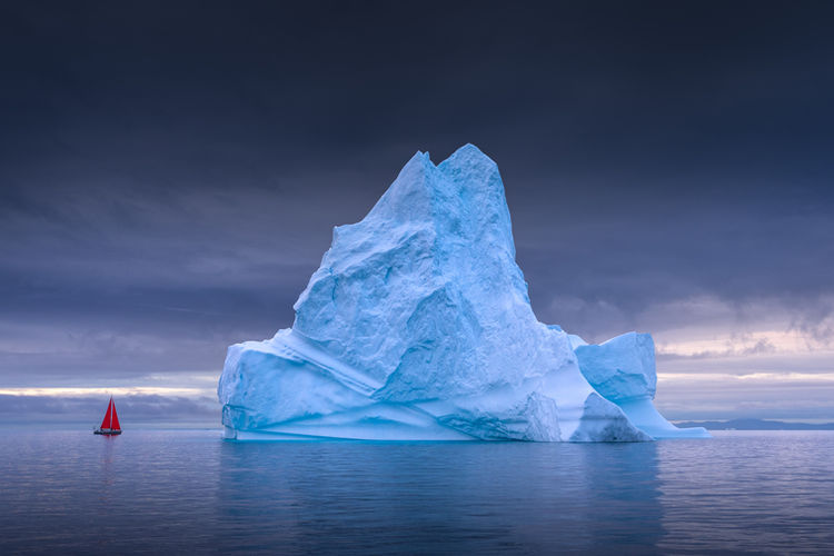 Red Sailboat Next to Iceberg in Disko Bay