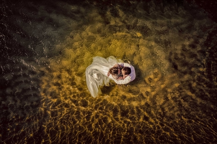 Aerial Photo of Bride and Groom Embracing in Water