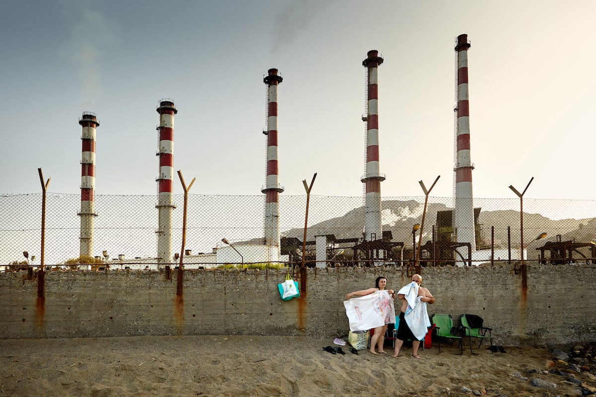 People on a Beach in Greece with a Factory in the Background
