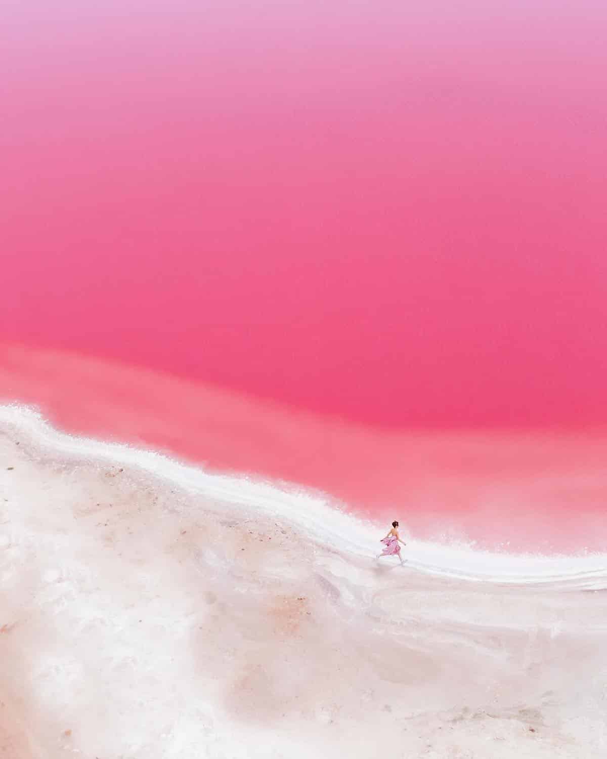 Aerial Photo of Woman Walking Across Pink Sea