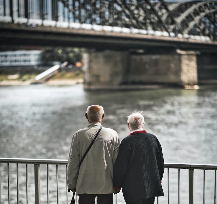 elderly couple look at a bridge on the water