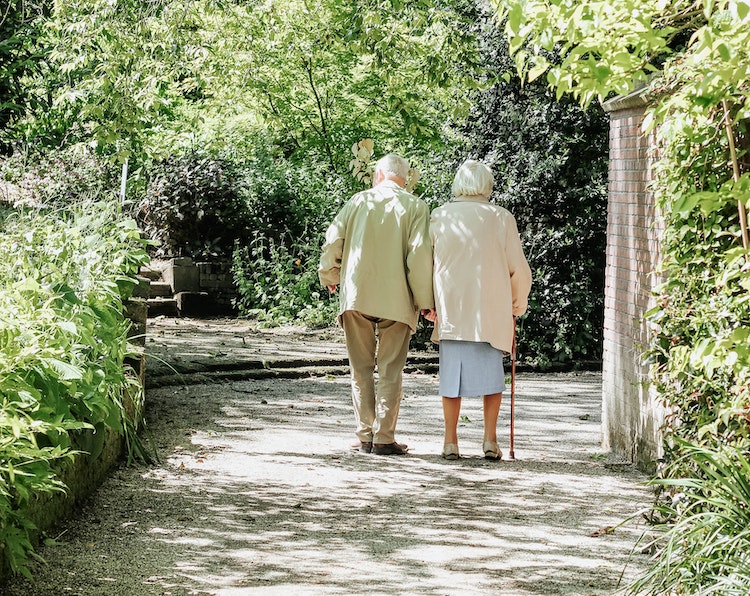 elderly couple walking through the trees