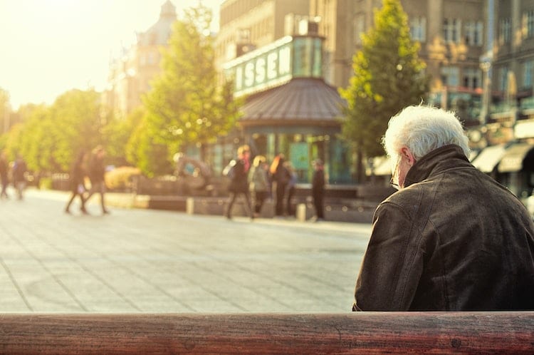 elderly person sitting alone on bench