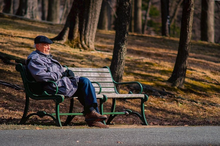 elderly man sits alone on bench