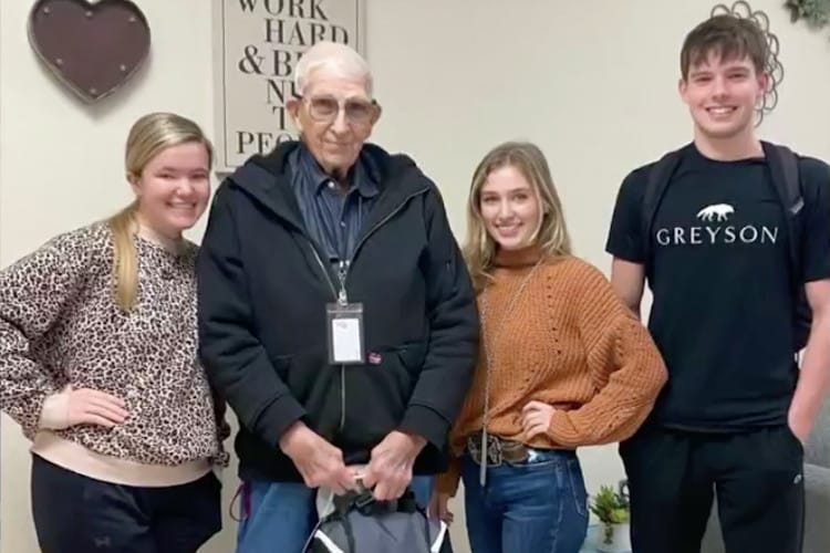 80-year-old custodian poses with three students who helped him when he had to come out from retirement to pay rent