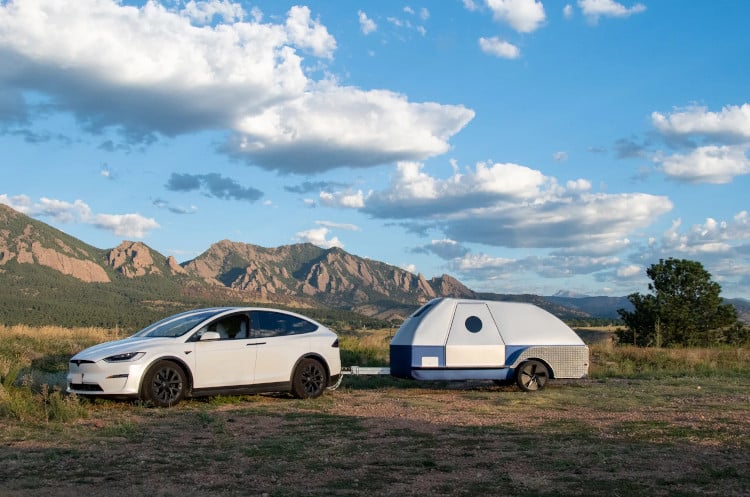 Colorado Teardrop trailer, attached to an EV, in front of a rocky landscape