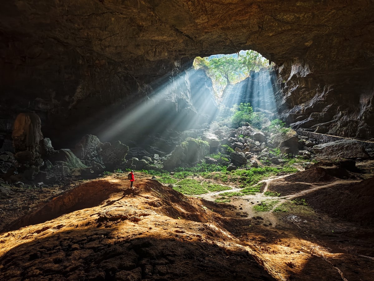 Man Hiking in a Cave with Sunlight Filtering Through