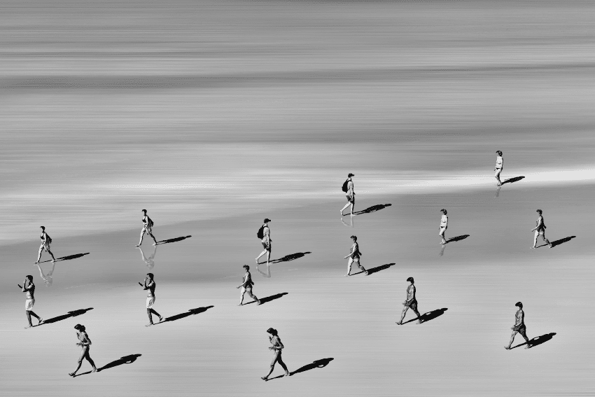 Black and white aerial photo of people walking on the beach