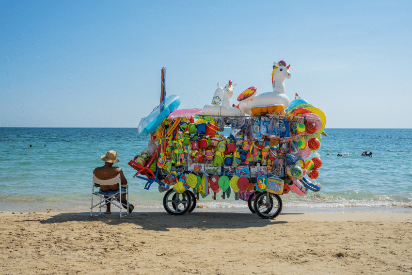 A beach seller sitting down next to his stall in Puglia, Italy