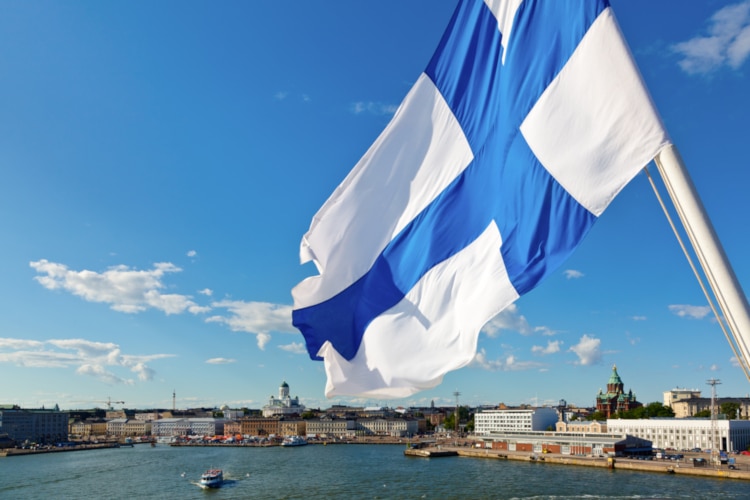 Flag of Finland, the happiest country in the world, flying over the skyline of Helsinki
