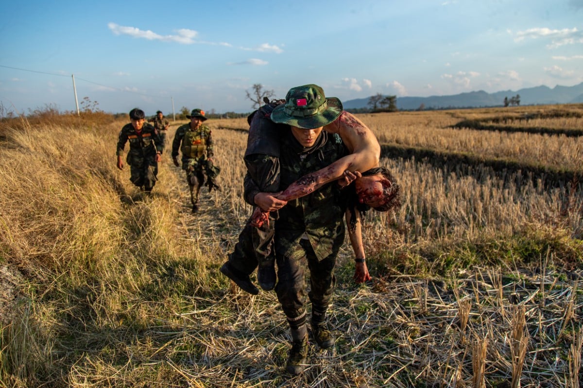 Resistance fighters from the People's Defense Forces (PDF) retreat with the body of a comrade in Myanmar