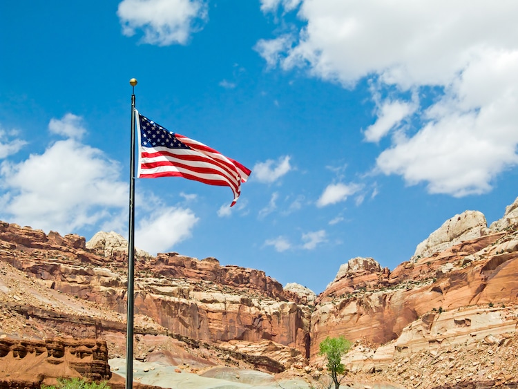 The flag of the United States of America flies in the desert landscape of Utah's Capitol Reef National Park.