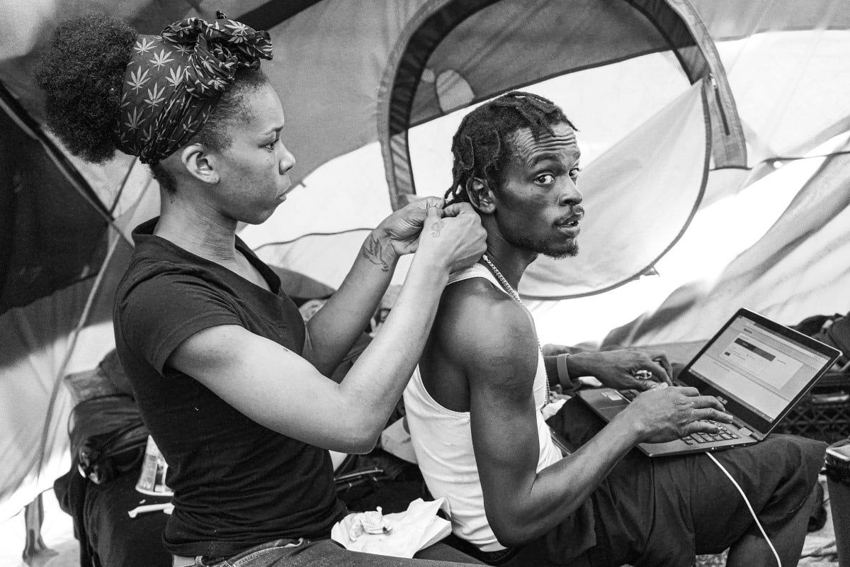 Woman braiding man's hair on Skid Row