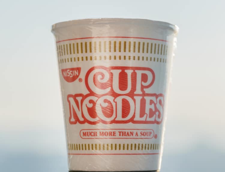 Nissin Cup noodle on sky background. Selective focus.