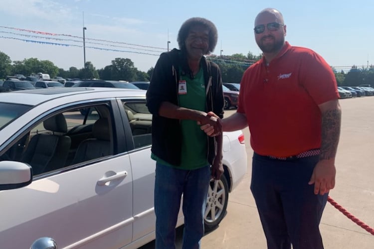 Mr. Troy, a custodian, shakes hands with salesman after getting a car after a fundraiser 