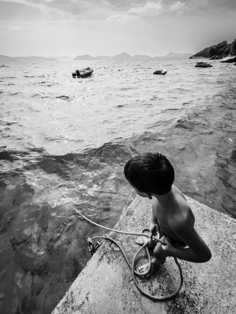Kid Lowering a Rope in the Water
