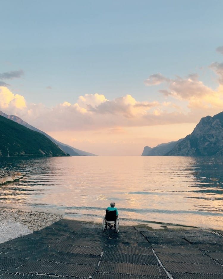 Elderly Person in Wheelchair Sitting on the Bank of Lake Garda in Italy