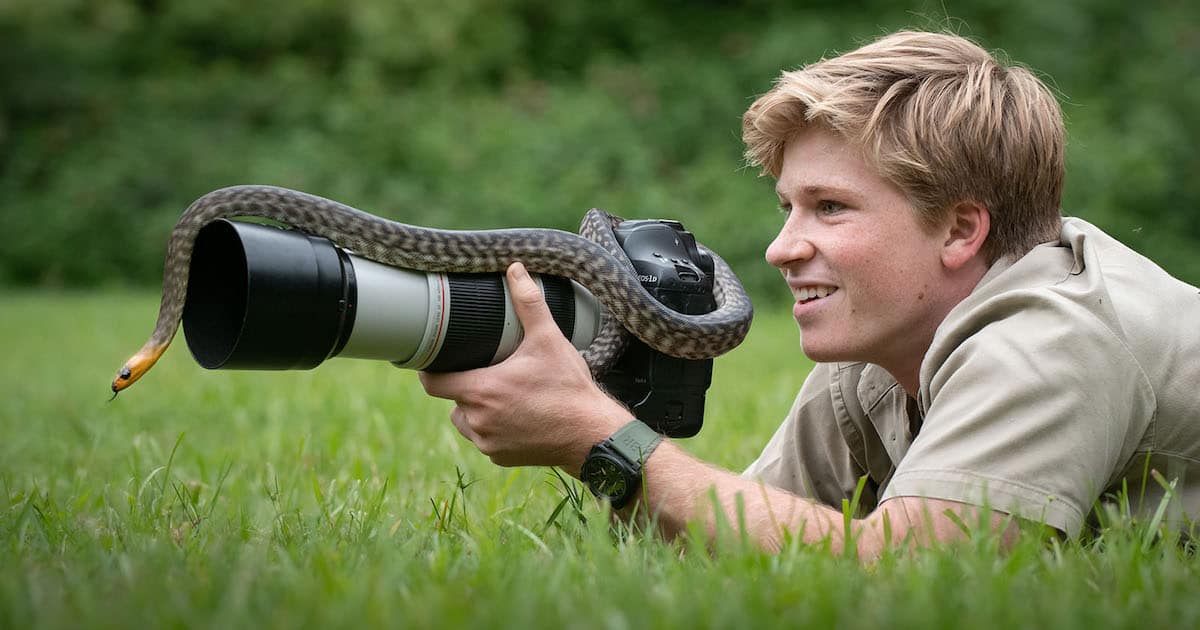 Robert Irwin holding a camera with a snake wrapped around it