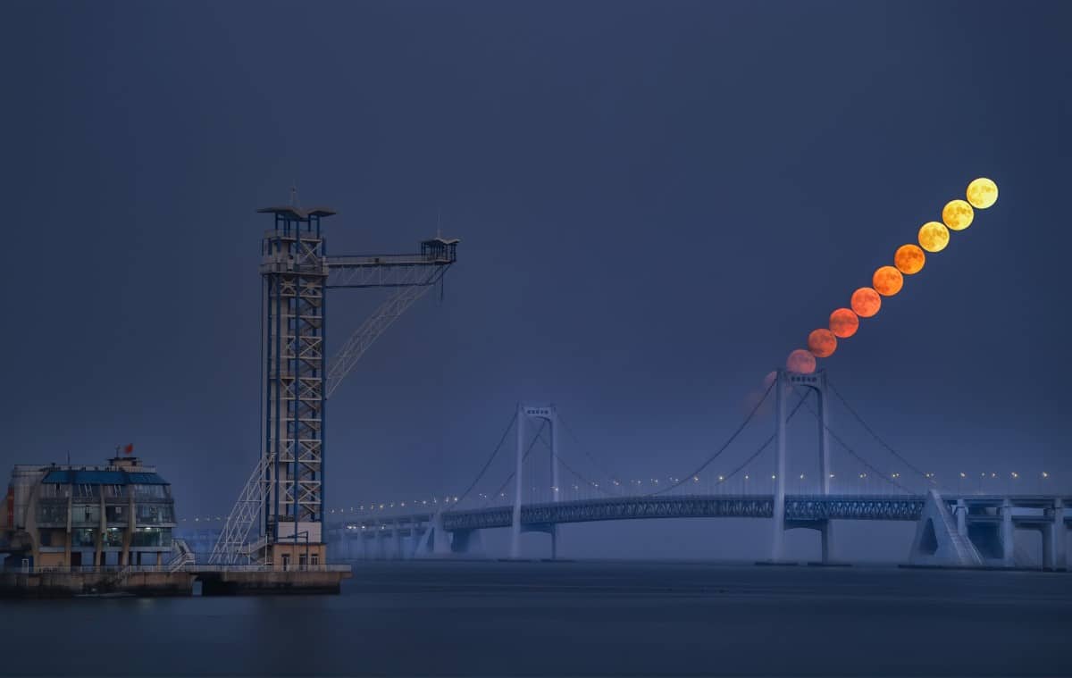 Photograph of a moonrise over the Xinghai Bay Bridge in Dalian