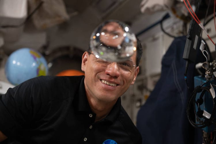 NASA astronaut behind a water bubble in zero gravity